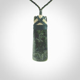 This photo shows a beautiful New Zealand jade toki suspended from a hand plaited adjustable cord. The binding around the top of the toki is a dark blue and creme colour. The cord is length adjustable which allows the pendant to be positioned where it suits you best. The toki was carved for us by Jen Hung who is a wonderful jade carver from New Zealand.