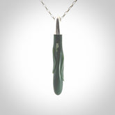 This picture shows a hand carved Inanga Pounamu, jade drop pendant with sterling silver cap and chain. The jade is a very dark green with a shimmer of light blue tones in the stone. It is suspended from a sterling silver clasp and we supply a sterling silver chain. Delivery is free worldwide.