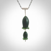 This is a very dark green flower bud pendant carved here in New Zealand by Josey Coyle. It is handmade carved jade double flower buds one placed above the other on a fine silver wire. The top is a T-shaped tube through which a silver necklace chain passes. The jade florets are handcarved from beautiful dark green New Zealand Marsden Jade and the chain is handmade from sterling silver wire.