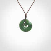 This picture shows a koru pendant, hand carved from New Zealand jade. We will provide this with an adjustable plaited cord. This has been hand carved by Kyohei Noguchi. One only pendant, shipped to you with express courier.