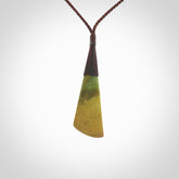 This photo shows a beautiful large sized flower jade drop. It is hand carved from a piece of New Zealand pounamu, with fascinating orange and green inclusions throughout the stone. We have this on a brown coloured, adjustable four plait cord. We ship this worldwide with an express courier service. Postage is free.