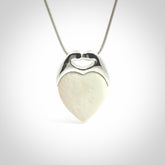 This picture shows a pendant that we have carved in a combination of sterling silver and woolly mammoth. It shows a symbolic kiss, with two heads coming together and both embracing a woolly mammoth heart. The necklace is a sterling silver chain.