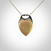 This picture shows a pendant that we have carved in a combination of sterling silver and woolly mammoth. It shows a symbolic kiss, with two heads coming together and both embracing a woolly mammoth heart. The necklace is a sterling silver chain.