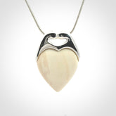 This picture shows a pendant that we have carved in a combination of sterling silver and woolly mammoth. It shows a symbolic kiss, with two heads coming together and both embracing a woolly mammoth heart. The necklace is a sterling silver chain.