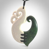 This photo shows a wonderful hand carved New Zealand jade and Whale Bone Manaia with hook pendant. The hook is suspended on a black four plait cord that is length adjustable.
