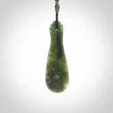 This is a sleek and slender hand carved New Zealand Jade mere pendant. The stone is a very beautiful green and the cord is either black, red or grey and is adjustable. The pendant has a light polish and just glows. Provided in a woven kete pouch.