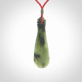 This is a sleek and slender hand carved New Zealand Jade mere pendant. The stone is a very beautiful green and the cord is either black, red or grey and is adjustable. The pendant has a light polish and just glows. Provided in a woven kete pouch.