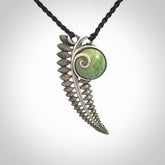 This is a hand carved Sterling Silver Fern leaf pendant with New Zealand flower Jade insert. This is a medium sized necklace and is provided with an adjustable black cord.