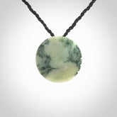 This piece is a small oval round, disc pendant hand carved in New Zealand jade.