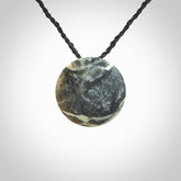 This piece is a small oval round, disc pendant hand carved in New Zealand jade.