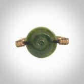 This picture shows a hand carved jade contemporary koru bracelet. It is a deep green Jade. It is a wonderful, delicate piece of jewellery. The cord is hand plaited and fixed with a black jade toggle. This bracelet was carved for us by Sheree Warren. Delivery is free worldwide.