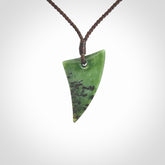 This is a lovely New Zealand Jade, pounamu niho drop pendant. Hand carved for us by Ric Moor. It is bound with an adjustable brown coloured cord which is length adjustable. Free worldwide shipping.