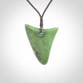 This is a lovely New Zealand Jade, pounamu niho drop pendant. Hand carved for us by Ric Moor. It is bound with an adjustable brown coloured cord which is length adjustable. Free worldwide shipping.