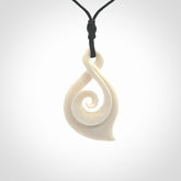 Hand carved twist with koru. Made from natural bone by NZ Pacific. Delivered with an adjustable cord.