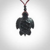 This picture shows a hand carved black jade turtle pendant. It is polished to a soft shine and has quite a lot of detail carved into the jade. The cord is a hand plaited burgundy, waxed polyester. Carved by NZ Pacific.