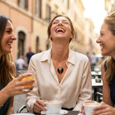 Three women laughing together outdoors, one wearing black jade heart necklace