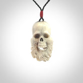 This picture shows a medium sized Deer Antler Bone pirate skull pendant that we have hand carved. The cord is a black colour and has a small red binding just above the pendant.