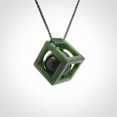A hand carved medium sized green Jade square box with ball inside necklace. The cord is adjustable in length. A medium sized hand made cube/box with ball necklace in green Jade.
