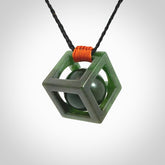 A hand carved medium sized green Jade square box with ball inside necklace. The cord is adjustable in length. A medium sized hand made cube/box with ball necklace in green Jade.