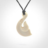 Hand carved bone whale tail pendant with black adjustable cord.