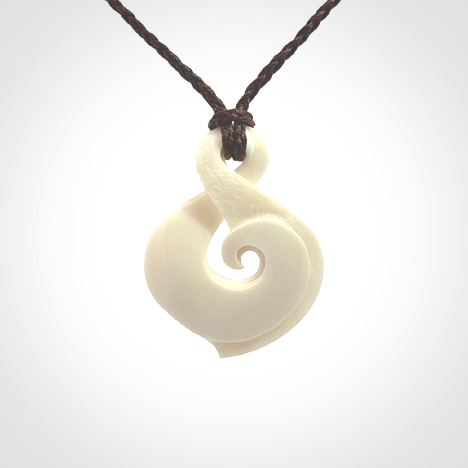 Hand carved bone twist pendant hand made by Peter Mitchell in New Zealand. This bone twist is provided with an adjustable brown cord and packaged in a woven kete pouch.