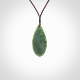 This photo shows a medium sized New Zealand jade drop shaped pendant. It a a lovely deep green jade. The cord is a four plait brown and is adjustable in length. One only medium, contemporary drop necklace from Jade, by Ric Moor.