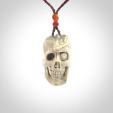 This picture shows a medium sized Deer Antler Bone robot skull pendant that we have hand carved. The cord is a plum colour and has a small orange binding just above the pendant.
