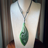 A beautiful large hand carved matau with koru pendant. Carved for us by Ross Crump from rare New Zealand jade. This is a wonderful pendant to gift to someone special.