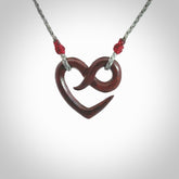 This piece is a fine, delicate eternity shaped pendant. It was carved from a lovely piece of red jasper stone. It is suspended on an grey braided cord that is length adjustable.