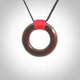 This piece is a fine, zen circle shaped pendant. It was carved from a lovely piece of red jasper stone. It is suspended on an black braided cord that is length adjustable.