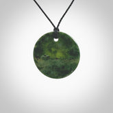 A lovely disc design with cupping on one side and the lightly convex form on the other - a little feature that captures the light and gives the piece a sense of movement and form. Hand made from New Zealand Jade by Ric Moor. Delivered with an adjustable black cord.