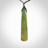 This is a lovely, large, New Zealand Flower Jade, pounamu drop pendant. Hand carved for us by Ric Moor. It is bound with an adjustable manuka green coloured cord which is length adjustable.