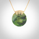 This piece is a medium sized cupped disc pendant. It was carved for us by Ric Moor from a lovely deep and milky green piece of New Zealand flower jade. It is suspended on a beige coloured braided cord that is length adjustable.