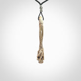 This picture shows a large sized Deer Antler Bone skull in skeleton hand pendant that we have hand carved. It is polished to a soft shine and is a very striking piece. The cord is a black colour and has a small grey floret binding just above the pendant.