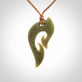 This photo shows a koru pendant carved from New Zealand Jade. We provide this piece with an adjustable gingernut brown coloured cord.