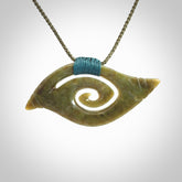 This photo shows a contemporary koru pendant carved from New Zealand Jade. We have added a Sea Moss Blue ridge-top binding with adjustable Olive Green cord.