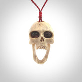 A hand carved SKULL pendant made from deer antler with Pyrope Garnet eyes. This is a work of art carved in deer antler, bone. We deliver this pendant to you on a plaited juicy red and passion red cord. Delivery with Express Courier is included in the price.