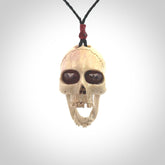 A hand carved SKULL pendant made from deer antler with Pyrope Garnet eyes. This is a work of art carved in deer antler, bone. We deliver this pendant to you on a plaited black cord. Delivery with Express Courier is included in the price.