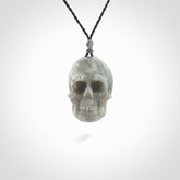 This picture shows a large sized Grey Moonstone skull pendant that we have hand carved. It is polished to a soft shine and is a very striking piece. The cord is black and has a small grey floret binding just above the pendant.