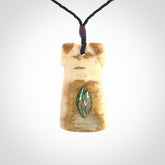 A stunning hand carved Woolly Mammoth Tusk Toki pendant. The toki has a small oval shaped piece of Pāua shell inset into the front face. This piece is bound with an adjustable cord. This is a little piece of Art to wear.