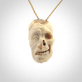 This photo shows a mummy skull pendant hand carved in deer antler. It is provided with a plaited cord necklace which is length adjustable.