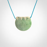 Hand carved Waimea pounamu disc pendant. These beautiful pieces have been carved for us by Raegan Bregmen and are quite beautiful. The soft green colours are lovely and are set off with a paradise blue cord and ice white ridge binding.