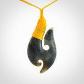 This is a beautiful jade hook with a little decorative koru carved into the bottom. It is a chunky piece but beautifully balanced so doesn't look heavy. The cord and the binding on the top is a yellow colour.