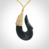 This photo shows a greenstone hook, or matau, pendant. It is a beautiful deep green jade. The cord is plaited and the length can be adjusted.