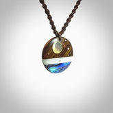 This photo shows a disc pendant hand carved from Lignum Vitae with premium nz paua shell, Mother of Pearl alongside; brass, copper and silver. This is a stand out one off necklace for those who appreciate art to wear. It is provided with a cord in brown that is a fixed length with Paua Shell Toggle. We ship this piece worldwide and shipping is included in the price.