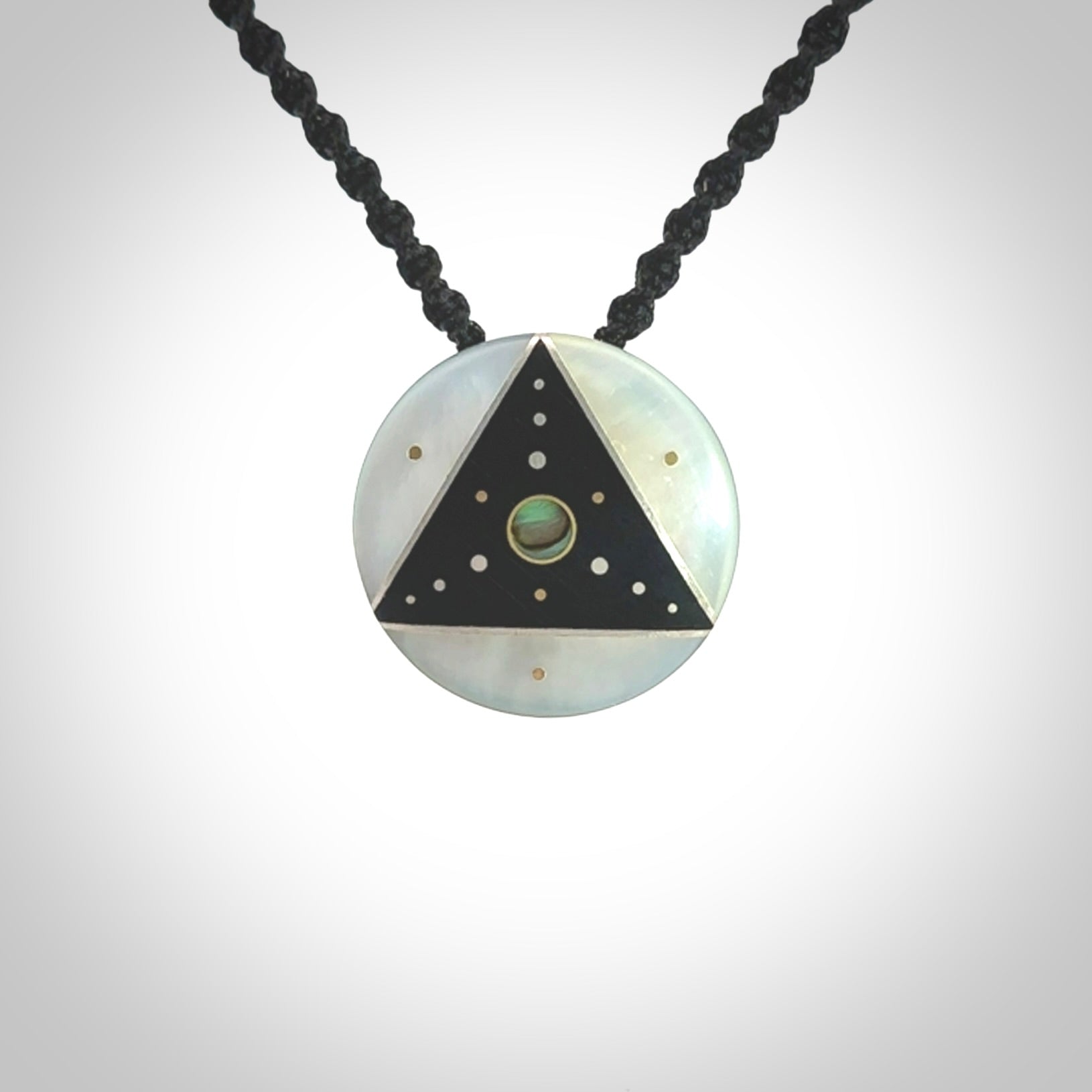 This photo shows a triangle disc pendant hand carved from ebony with nz paua shell, Mother of Pearl alongside; brass and silver. This is a stand out one off necklace for those who appreciate art to wear. It is provided with a cord in black that is a fixed length with Paua Shell Toggle. We ship this piece worldwide and shipping is included in the price.