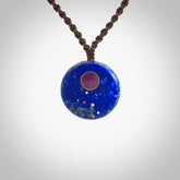 This photo shows a medium sized disc pendant hand carved from Lapis Lazuli with Sugilite inlay and copper, gold, and silver. This is a stand out one off necklace for those who appreciate art to wear. It is provided with a cord in black that is a fixed length with Paua Shell Toggle. We ship this piece worldwide and shipping is included in the price.