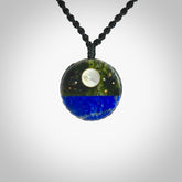 This photo shows a medium sized disc pendant hand carved from Lapis Lazuli and New Zealand Jade with Mother of Pearl inlay and copper, gold, and silver. This is a stand out one off necklace for those who appreciate art to wear. It is provided with a cord in black that is a fixed length with Paua Shell Toggle. We ship this piece worldwide and shipping is included in the price.