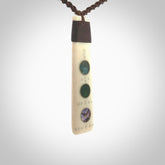 This photo shows a medium sized Toki pendant hand carved from bone with New Zealand Pounamu, Jade and Aotea Stone, Paua Shell inlay alongside; brass and silver. This is a stand out one off necklace for those who appreciate art to wear. It is provided with a cord in brown that is a fixed length with Paua Shell Toggle. We ship this piece worldwide and shipping is included in the price.