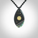 This photo shows a medium sized drop pendant hand carved from Ebony wood with Mother of Pearl and Paua Shell inlay, alongside; brass, copper and silver. This is a stand out one off necklace for those who appreciate art to wear. It is provided with a cord in black that is a fixed length with Paua Shell Toggle. We ship this piece worldwide and shipping is included in the price.